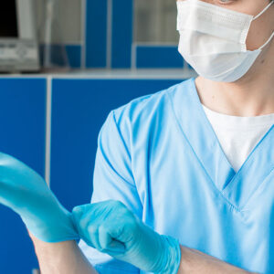 image of nurse with mask and hair covering on putting on gloves