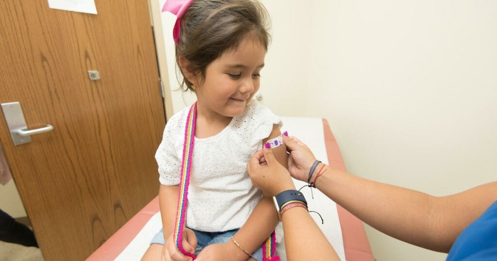 RN administering a vaccine to a child